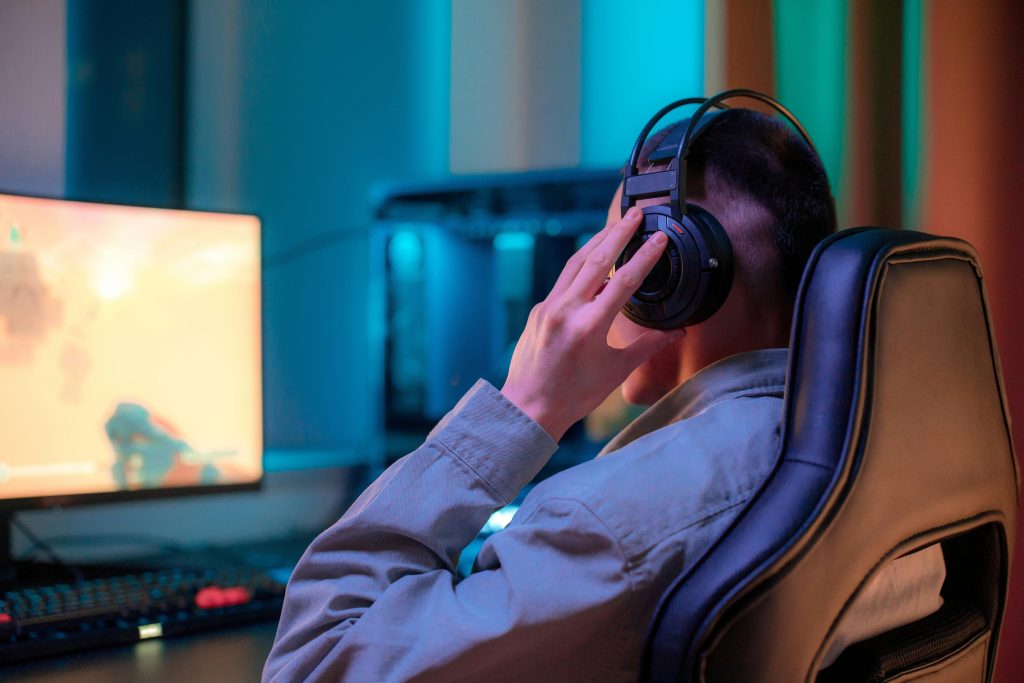 A man in headphones gaming on a computer at a stylish desk setup.